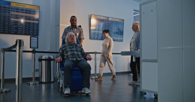 Havaalanı Terminali 'ndeki güvenlik kontrol noktası: Tekerlekli sandalyeden kalkan yaşlı adam, metal dedektör tarama kapısından geçen güvenlik görevlisi yardım ediyor. Tarama İşlemleri sırasında Yaşlı Turist.