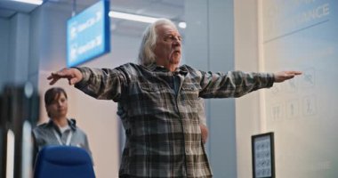 Güvenlik Kontrol Noktası: Afrikalı Amerikalı Ulaşım Güvenliği Memuru Yaşlı Adamı Kontrol Ediyor, Tekerlekli Sandalyeye Oturan Adam. Uçağa binmek için havaalanı terminalinde yolcu tarama prosedürleri. Kıdemli Gezgin Seyahate çıkıyor