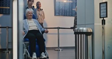 Havaalanı Terminali 'ndeki güvenlik kontrol noktası: Yaşlı kadının tekerlekli sandalyeden kalkmasını denetleyen kadın güvenlik görevlisi. Uçağa binmek için Ulaşım Güvenliği İdaresi İnceleme Prosedürleri. Kıdemli Turist Seyahate Çıkıyor.