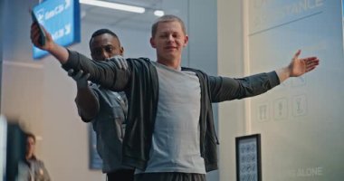 Güvenlik Kontrol Noktası: Afro-Amerikan Ulaşım Güvenlik Subayı Havaalanı Terminalinde Genç Adamı Protez Bacaklı Kontrol Ediyor. Uçağa binmek için yolcu tarama prosedürleri. Engelli Gezgin Seyahate Çıkıyor