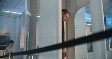 Havaalanı Terminalindeki güvenlik kontrol noktası: Protez bacaklı bir adam ve Metal dedektöründen geçen yetişkin bir kadın biniş için kapıları tarıyor. TSA tarama prosedürleri sırasında çeşitli turistler.