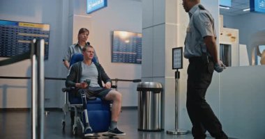 Havaalanı Terminali 'ndeki güvenlik kontrol noktası: Tekerlekli sandalyedeki protez bacaklı genç adamı denetleyen Afrikalı Amerikan Güvenlik Subayı. Uçağa binmek için tarama prosedürleri. Engelli Turist.