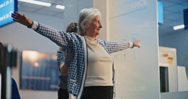 Güvenlik Kontrol Noktası: Havaalanı Terminali 'nde yaşlı kadını kontrol eden kadın havaalanı görevlisi, tekerlekli sandalyeye binen kadın. Uçağa binmek için yolcu tarama prosedürleri. Engelli kıdemli gezgin..