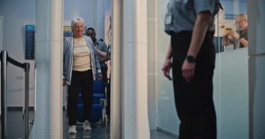 Güvenlik Kontrol Noktasındaki Kıdemli Gezgin: Tekerlekli sandalyeden kalkan yaşlı kadın, Havaalanı Terminali 'ndeki X-ray Metal Detektör Tarayıcısını geçiyor, Havaalanı Personel Yardım Hatunu. Yolcu Ekran Prosedürleri.