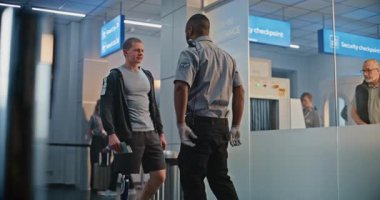 Güvenlik Kontrol Noktası: Afro-Amerikan Ulaşım Güvenlik Subayı Havaalanı Terminalinde Genç Adamı Protez Bacaklı Kontrol Ediyor. Uçağa binmek için yolcu tarama prosedürleri. Engelli Gezgin Seyahate Çıkıyor