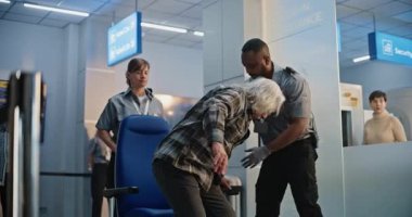 Güvenlik Kontrol Noktası: Tekerlekli sandalyedeki yaşlı adamı ve havaalanı terminalindeki yaşlı kadını kontrol eden çeşitli havaalanı görevlileri. Uçağa binmek için yolcu tarama prosedürleri. Kıdemli Gezginler Seyahate Çıkıyor.