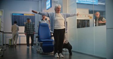 Havaalanı Terminali 'ndeki güvenlik kontrol noktası: Tekerlekli sandalyedeki yaşlı kadını denetleyen çeşitli güvenlik görevlileri ve uçağa binmek için yaşlı adam. TSA tarama prosedürleri. Kıdemli Turistler Seyahate Çıkıyor.