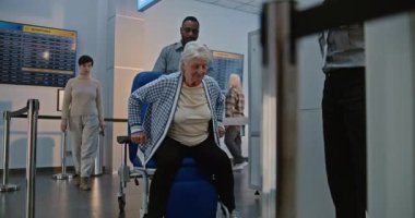 Güvenlik Kontrol Noktasındaki Yaşlı Gezgin: Tekerlekli sandalyeden kalkan yaşlı kadın, Havaalanı Terminali 'ndeki X-ray Metal Detektör Tarayıcısını geçiyor, Havaalanı Personel Yardım Hatunu. Yolcu Ekran Prosedürleri.