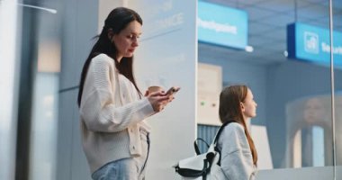 Kalabalık Havaalanı Terminali: Yaramaz Kız Annesiyle Konuşuyor ve Tartışıyor. Aile, Tatil Gezisi 'ne çıkmak üzere, Airline Hub' ın biniş salonunda uçuşu bekliyor. Çeşitli İnsanlar ve Havalimanı Personeli Yürüyüşü