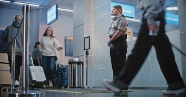 Kalabalık Uluslararası Havaalanı Terminalinde Bavulda Yürüyen Yolcular. Kadın Güvenlik Subayı, Uçağa binmek için kadının kapısını bulmasına yardım ediyor. Gezginler Tatile Çıkıyor