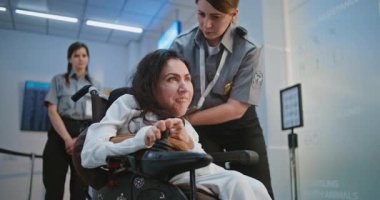 Güvenlik Kontrol Noktası 'ndaki tarama prosedürleri: Havaalanı Terminali' nde fiziksel engelli bir kadını kontrol eden kadın TSA memuru. Havalimanı İşçisi, Yolcuyla Yolcu Uçağı Uçuşu için Tekerlekli Sandalyede Yürüyor