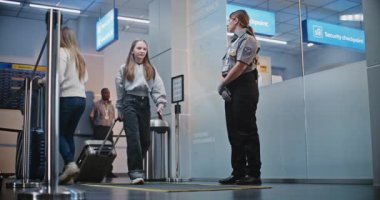 Kalabalık Uluslararası Havaalanı Terminali: Güvenlik Kontrol Noktasında Duran Güvenlik Personeli, Biniş Uçuşlarına Giden Çeşitli İnsanlar, Gelen ve Giden Bilgileri Denetleme Kurulu.