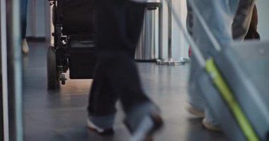 Kalabalık Uluslararası Havaalanı Terminali: Uçağa binmek için bavullar ve bavullarla yürüyen çeşitli insanların diz üstü çekimleri. Tekerlekli sandalyedeki engelli yolcu. Turizm ve Seyahat.