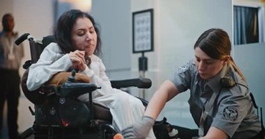 Güvenlik Kontrol Noktası: Havaalanı Terminali 'nde engelli bir kadını kontrol eden kadın havaalanı görevlisi. Uçağa binmek için yolcu tarama prosedürleri. Tekerlekli sandalyedeki gezgin seyahate çıkıyor. Doli Vuruşu.