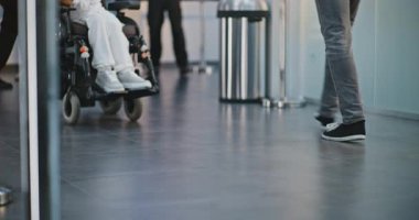 Kalabalık Uluslararası Havaalanı Terminali: Uçağa binmek için bavulla birlikte yürüyen çeşitli insanların diz üstü çekimleri. Tekerlekli sandalyedeki engelli yolcu. Turizm ve Seyahat. Yavaş çekim.