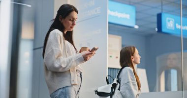 Kalabalık Havaalanı Terminali: Yaramaz Kız Annesiyle Konuşuyor ve Tartışıyor. Aile, Tatil Gezisi 'ne çıkmak üzere, Airline Hub' ın biniş salonunda uçuşu bekliyor. Çeşitli İnsanlar ve Havalimanı Personeli Yürüyüşü