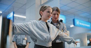 Havaalanı Terminali 'ndeki güvenlik kontrol noktası, kadın havaalanı güvenlikçisi kızı kontrol ediyor, tarama prosedürleri uyguluyor. Güvenlik işçisi, genç kızla birlikte uçağa binmek için yürüyüşe çıktı. Genç Gezgin Tatile Çıkıyor.