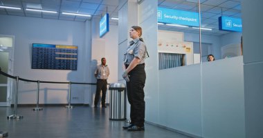 Güvenlik Kontrol Noktası 'ndaki tarama prosedürleri: Havaalanı Terminali' nde fiziksel engelli bir kadını kontrol eden kadın TSA memuru. Havalimanı İşçisi, Yolcuyla Yolcu Uçağı Uçuşu için Tekerlekli Sandalyede Yürüyor