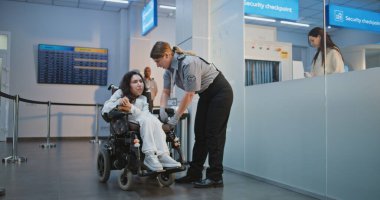 Havaalanı İşçisi, Havaalanı Terminali 'ndeki Güvenlik Kontrol Noktasında Engelli Yolcuyla Yürüyor. Kadın Ulaşım Güvenliği Memuru, Biniş için Fiziksel Özürlü Kadını Kontrol Ediyor.