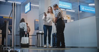 Kalabalık Uluslararası Havaalanı Terminalinde Bavulda Yürüyen Yolcular. Kadın Güvenlik Subayı, Uçağa binmek için kadının kapısını bulmasına yardım ediyor. Gezginler Tatile Çıkıyor