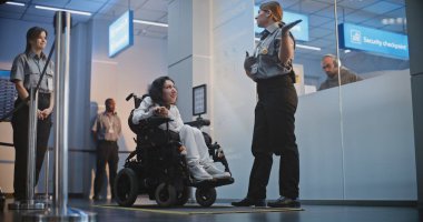 Havaalanı Terminali 'ndeki güvenlik kontrol noktası, kadın güvenlik görevlisi tekerlekli sandalyedeki kadını teftiş etti. TSA tarama prosedürleri. Yolcu ile Yürüyen İşçi Uçağa Biniş İçin Fiziksel Engelli.