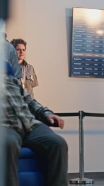 Havaalanı Terminali 'ndeki güvenlik kontrol noktası: Afrikalı Amerikan Güvenlik Subayı Tekerlekli sandalyeden kalkan yaşlı adamı denetliyor. Tarama prosedürleri. Engelli kıdemli turist. Dikey Çekim.