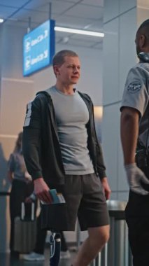 Güvenlik Kontrol Noktası: Afro-Amerikan Ulaşım Güvenlik Subayı Havaalanı Terminalinde Genç Adamı Protez Bacaklı Kontrol Ediyor. Uçağa binmek için yolcu tarama prosedürü. Engelli bir gezgin. Dikey Çekim