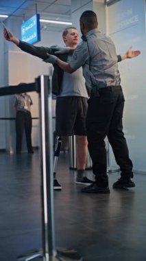 Havaalanı Terminali 'ndeki güvenlik kontrol noktası: Uçuş için protez bacaklı Afrikalı Amerikan Güvenlik Subayı Denetleme Görevlisi. TSA tarama prosedürleri. Engelli turist. Tam doz. Dikey Çekim.