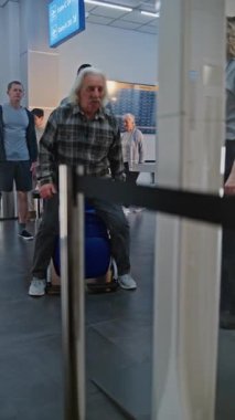 Güvenlik Kontrol Noktasındaki Kıdemli Gezgin: Tekerlekli sandalyeden kalkan yaşlı adam, Havaalanı Terminalindeki X-ray tarayıcısını geçiyor, Havaalanı Personel Yardım Adamı. Yolcu tarama prosedürleri. Dikey Çekim.