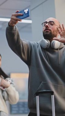 Kalabalık Havaalanı Terminali: Akıllı Telefon 'da Video Kaydı Yapan Adam. Afrikalı Amerikalı güvenlik görevlisi video kaydının yasaklanması konusunda uyardı. Arka planda, çeşitli insanlar yürüyor. Dikey Çekim.