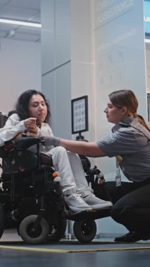 Güvenlik Kontrol Noktası Tarama Prosedürleri: Havaalanı Terminali 'ndeki Motorize Tekerlekli Sandalyede Kadın Kontrol Görevlisi. Yolcu ile Yürüyen İşçi Engelli Uçuşu. Dikey Çekim.