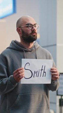 Kalabalık Uluslararası Havalimanı Terminali 'nde Ulaştırma Servisi: Havaalanı Şoför Holding İsim Tabelası, İş Aktarımı Yolcuları Buluşması. Orta boy shot. Dikey Çekim.