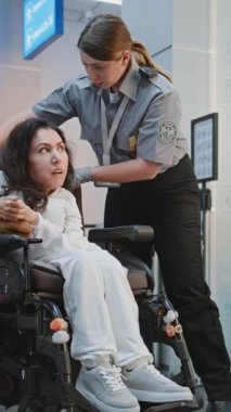 Havaalanı Terminali 'ndeki Güvenlik Kontrol Noktası Tekerlekli Sandalyedeki Kadın Güvenlik Görevlisi. Tarama prosedürleri. Fiziksel Engelli Yolcu. Dolly Shot. Dikey Çekim