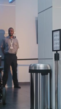 Güvenlik Kontrol Noktası: Havaalanı Terminali 'nde engelli bir kadını kontrol eden kadın havaalanı görevlisi. Uçağa binmek için yolcu tarama prosedürleri. Tekerlekli sandalyedeki gezgin seyahate çıkıyor. Dikey Çekim.