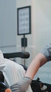 Güvenlik Kontrol Noktası: Havaalanı Terminali 'nde engelli bir kadını kontrol eden kadın havaalanı görevlisi. Uçağa binmek için yolcu tarama prosedürleri. Tekerlekli sandalyedeki gezgin seyahate çıkıyor. Dikey Çekim.