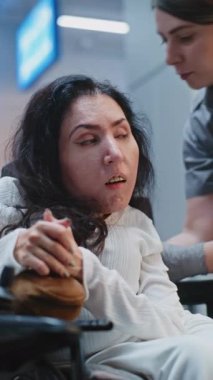 Güvenlik Kontrol Noktası: Havaalanı Terminali 'nde fiziksel engelli bir kadını kontrol eden kadın havaalanı görevlisi. Uçuş için yolcu tarama prosedürleri. Tekerlekli sandalyedeki gezgin seyahate çıkıyor. Dikey Çekim.