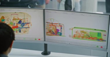 Havaalanı kontrol noktası: Kadın güvenlik görevlisi bilgisayar ekranlarında metal dedektörü taraması yapıyor. Arka planda, bavullar ve çantalar Güvenlik Kontrolünden sonra X-ray Makinesinden taşınıyor.