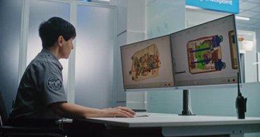 Havaalanı Güvenlik Kontrol Noktası: Bilgisayar Ekranları Yazılım Kullanılarak Bavul X-ray taramasını izleyen kadın güvenlik subayı. Arka planda, Tarama İşlemi sırasında Çeşitli Bavullu İnsanlar.