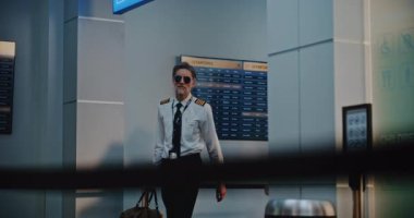 Profesyonel Uçuş Ekibi: Gözlüklü Hava Yolları Pilotu ve Uluslararası Havaalanı Terminalinden geçerken, Ticari Uçuş için Bavulla Yürüyen Üniformalı İki Güzel Uçuş Görevlisi. Yavaş Hareket.