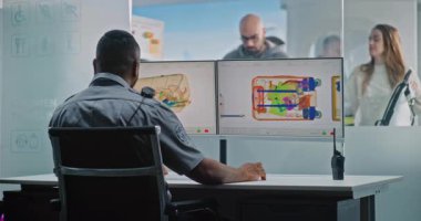 Havaalanı Güvenlik Kontrol Noktası: Afrikalı Amerikalı Ulaşım Güvenliği İşçisi Bilgisayar monitörlerindeki bagaj taramasını X-ray Metal Detektörü ile kontrol ediyor. Eşya Taşıma İşlemi Sürecinde Çeşitli Yolcular.