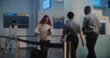 Kalabalık Uluslararası Havaalanı Terminali 'nde bavullu çeşitli insanlar. Profesyonel Havayolu Başkomiseri ve iki hostesi Ticari Uçuş Yürüyüşü Güvenlik Kontrol Noktasından Geçiyor.