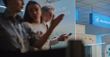 Üniformalı kahve içen, telefon kullanan, ticari uçuşu bekleyen profesyonel pilot. Bir kadın havaalanına geliyor Kaptan ve Smartphone 'da selfie çekiyor. Kalabalık Uluslararası Havaalanı Terminali.