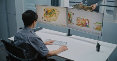 Havaalanı Güvenlik Kontrol Noktası: Bilgisayar monitörlerindeki bagaj taramasında X-ışını metal dedektörünü kontrol eden kadın TSA işçisi. Arka planda, bavul taraması sırasında çeşitli yolcular.
