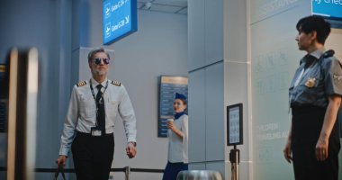 Havaalanı Terminalinde Uçuş Ekibi: Havaalanı Kaptanı ve İki Güzel Hostes, Güvenlik Kontrol Noktasında Bayan TSA İşçisinin yanından geçerken, 