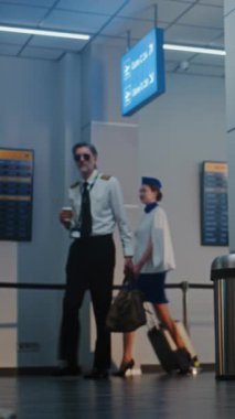 Havaalanı Terminalinde Uçuş Ekibi: Olgun Havayolu Pilotu ve İki Güzel Uçuş Görevlisi, Uçuş için Bavulla Geziniyor, Güvenlik Subayının yanından geçiyoruz. Tam doz. Dikey Çekim.