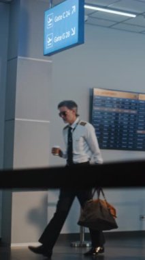 Havaalanı Terminalinde Uçuş Ekibi: Havaalanı Kaptanı, Uçuş için Bavullarla Yürüyen İki Güzel Hostes, Güvenlik Kontrol Noktasında Afro-Amerikan Subayın yanından geçiyoruz. Dikey Çekim.