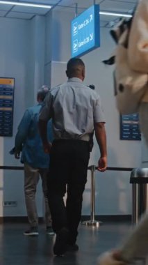 Kalabalık Uluslararası Havaalanı Terminali 'nde bavullu çeşitli yolcular. Uçak Pilotu ve Bavullu İki Uçuş Görevlisi Güvenlik Kontrol Noktasından Uçak Yürüyüşü Geçiyorlardı. Dikey Çekim