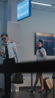 Havaalanı Terminali: Olgun Hava Yolları Pilotu ve İki Güzel Uçuş Görevlisi, Afro-Amerikan Güvenlik Subayının yanından geçerken, Uçuş Uçuşu için bavulla birlikte yürüyorlar. Ağır çekim. Dikey Çekim