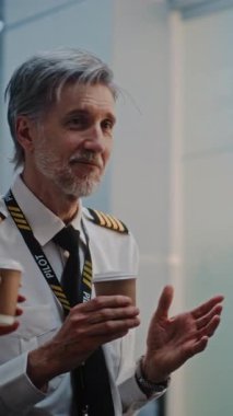 Uçuş Ekibi: Uçak Pilotu Üniformalı İki Uçuş Görevlisiyle İletişim, Kahve İçme, Kalabalık Uluslararası Havaalanı Terminalinde Ticari Uçuş Bekleme. Ağır çekim. Dikey Çekim.