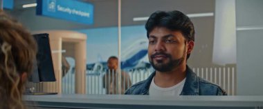 Havaalanı kontrol gişesi: Hintli Adam Yüz Tanıma Taramasıyla Biyometrik Verileri Doğrulayarak Havayolu Ajanı 'na Belge ve Uçak Biletleri Veriyor. Uluslararası Havalimanı Terminalinde Pasaport Denetimi.